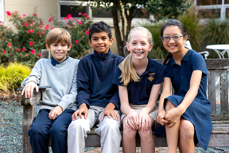 happy young kids sitting outside on a bench together