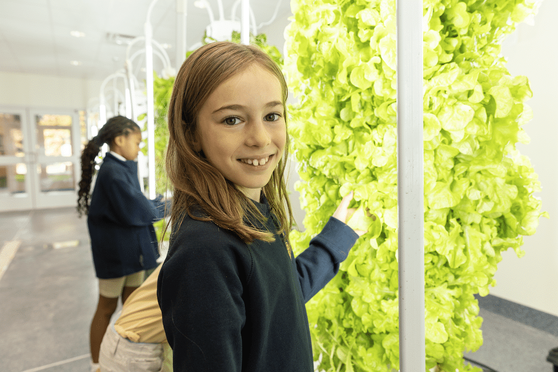 HRA student smiling in front of hydroponics