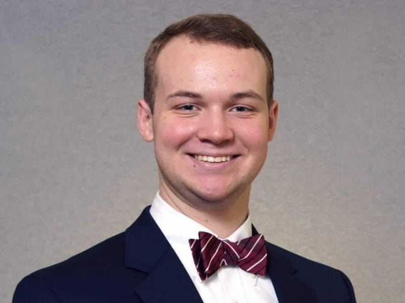 portrait of a graduate young man wearing black suit and bow tie