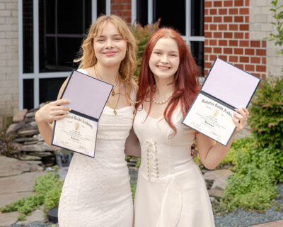 Charlotte Goddin and CJ Erwin, 2025 graduates of Hampton Roads Academy, proudly display their diplomas