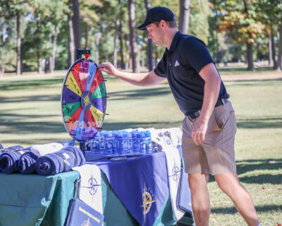 Thomas Capstick spins the "Beal Wheel" for prizes at the 2024 HRA Golf Classic