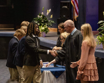 HRA Honor Council faculty advisor Jeremy Clover, joined by Lexi Trudeau, shakes ninth graders' hands after they sign the Honor Banner