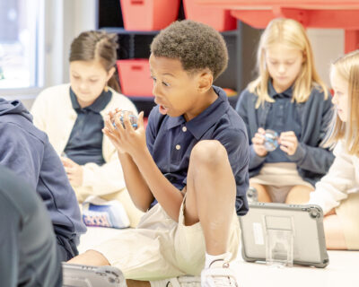 HRA fourth grader looks on a Sphero robot with excitement