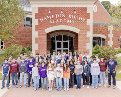 Seniors in college attire in front of Hampton Roads Academy