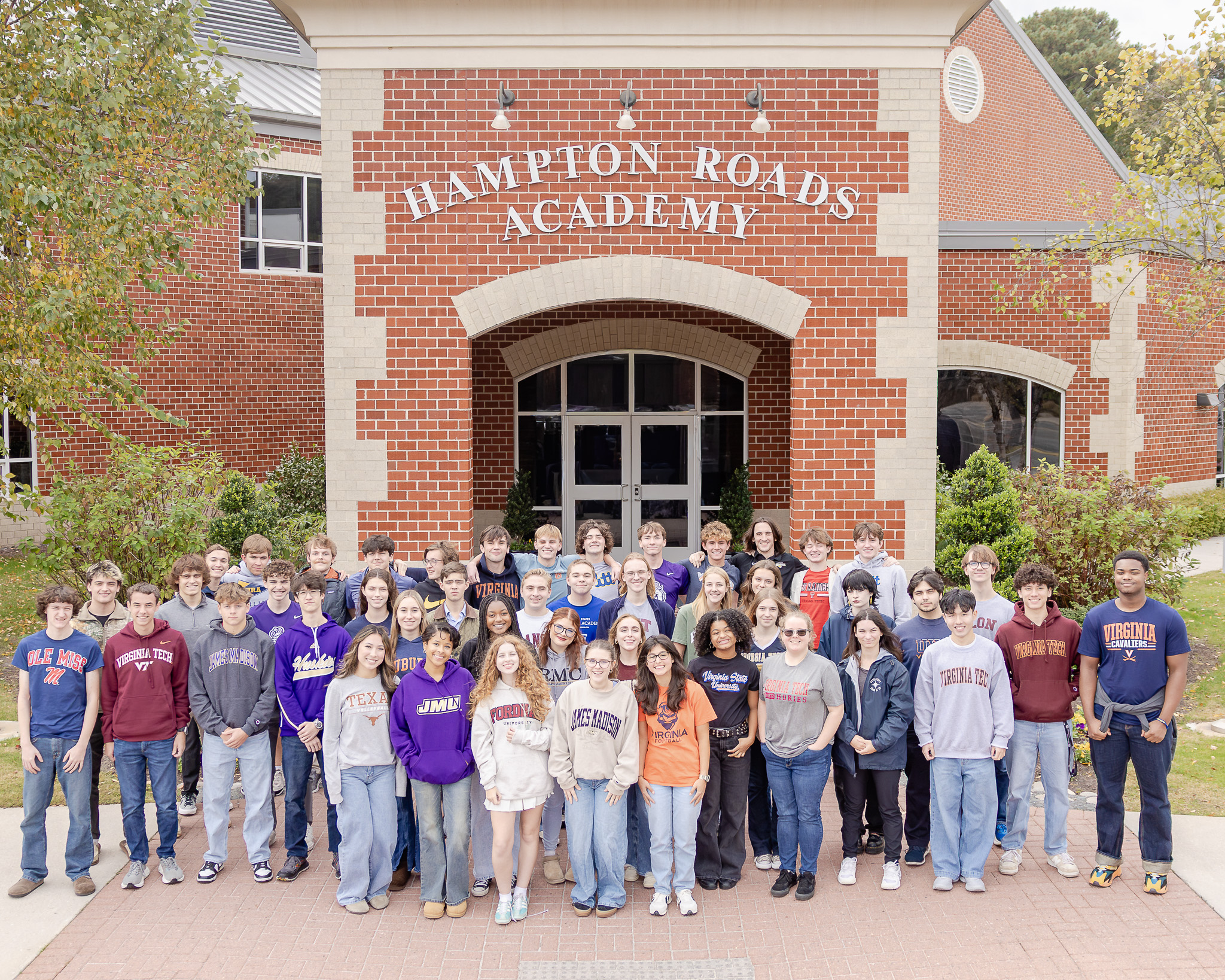 Seniors in college attire in front of Hampton Roads Academy
