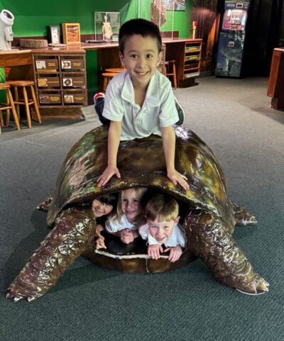 HRA kindergarteners in and on top of a tortoise shell at the Virginia Living Museum