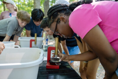 HRA seventh graders studying specimens under the microscope during the May 2026 field trip to Mariners' Lake