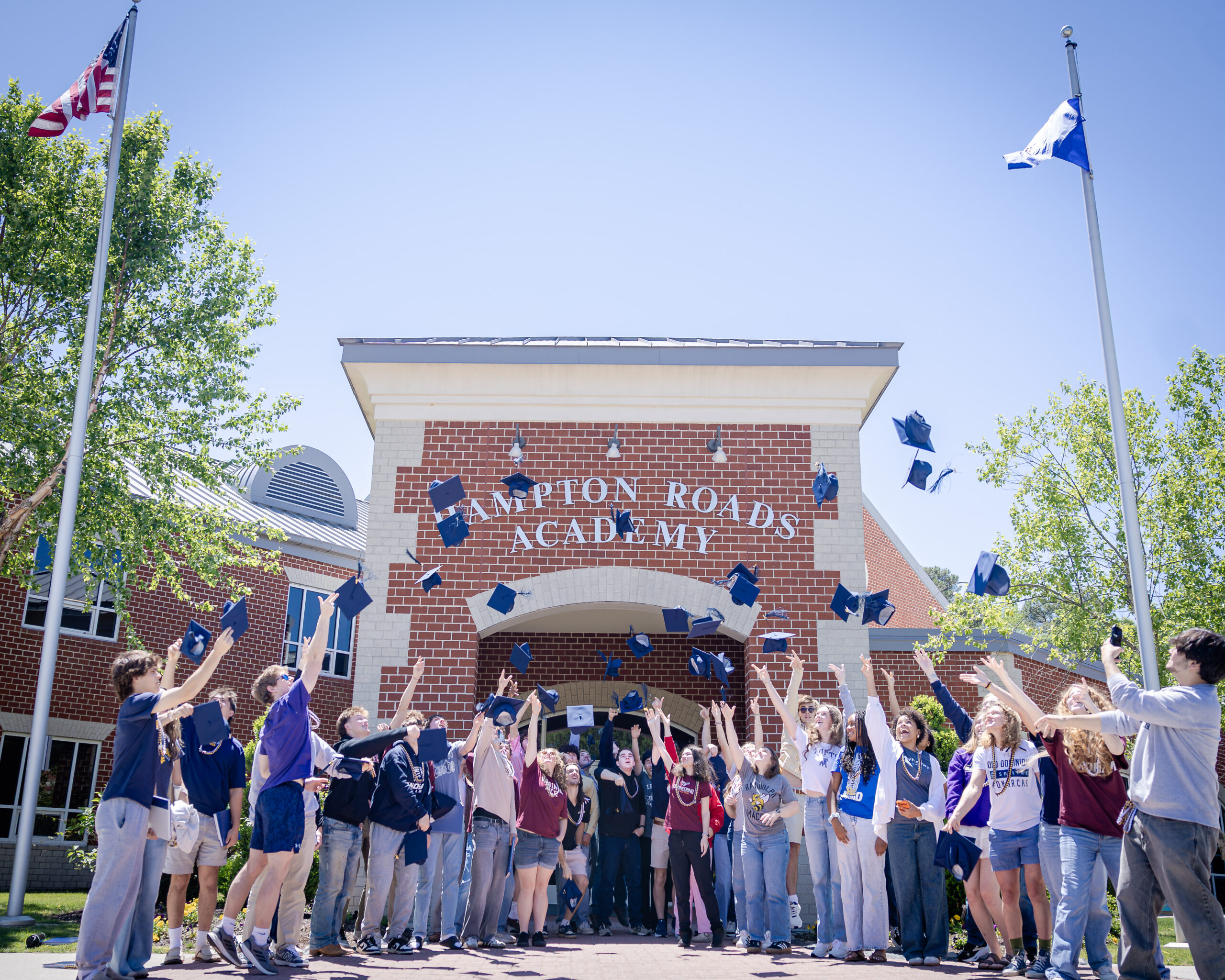 The HRA Class of 2026 tosses their graduation caps in front of the school