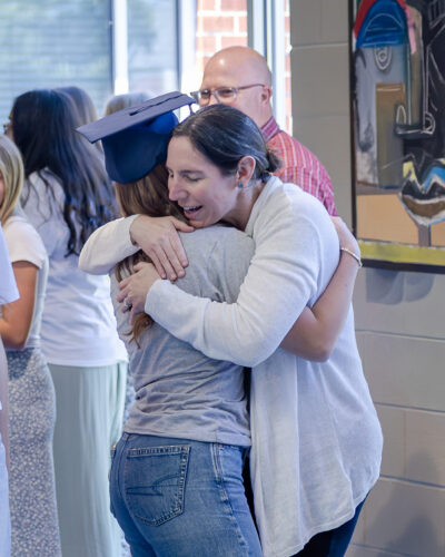 HRA Upper School science teacher Lauren Oaks hugging a student during the 2026 HRA Senior Parade