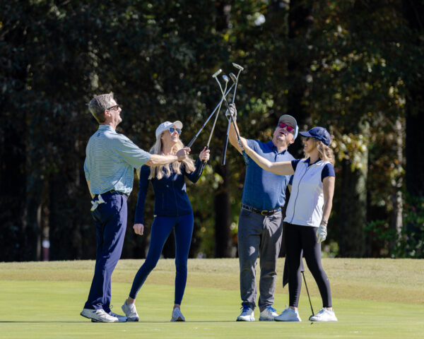 Players raising their clubs in celebration at the HRA Golf Classic