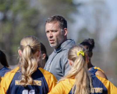 HRA varsity boys and girls soccer coach Chris Mills on the pitch with the girls team