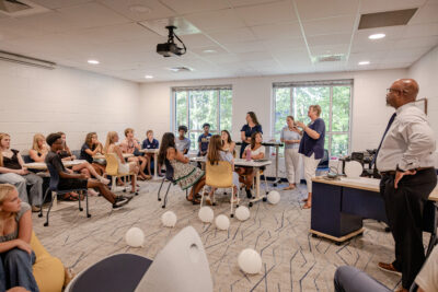 Seated HRA students listening to a presentation by faculty members in the Student Support Center