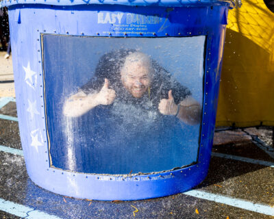 Middle and Upper School choir director Marshall Severin smiling with two thumbs up under water in the dunk tank at the 2025 HRA Fall Festival