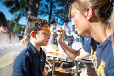 An Upper School student painting a Lower School student's face at the 2025 HRA Fall Festival