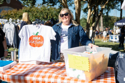 Parent volunteer holding a pumpkin T-shirt at HRA's 2025 Fall Festival