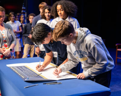 HRA eighth graders signing the Honor Banner during the 2026 Middle School Honor Assembly