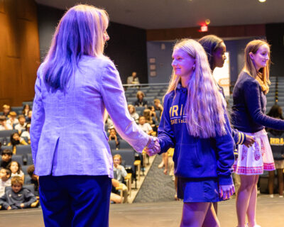 HRA Director of Middle School Abigail Whorley shakes hands with an eighth-grade student during the 2026 Middle School Honor Assembly