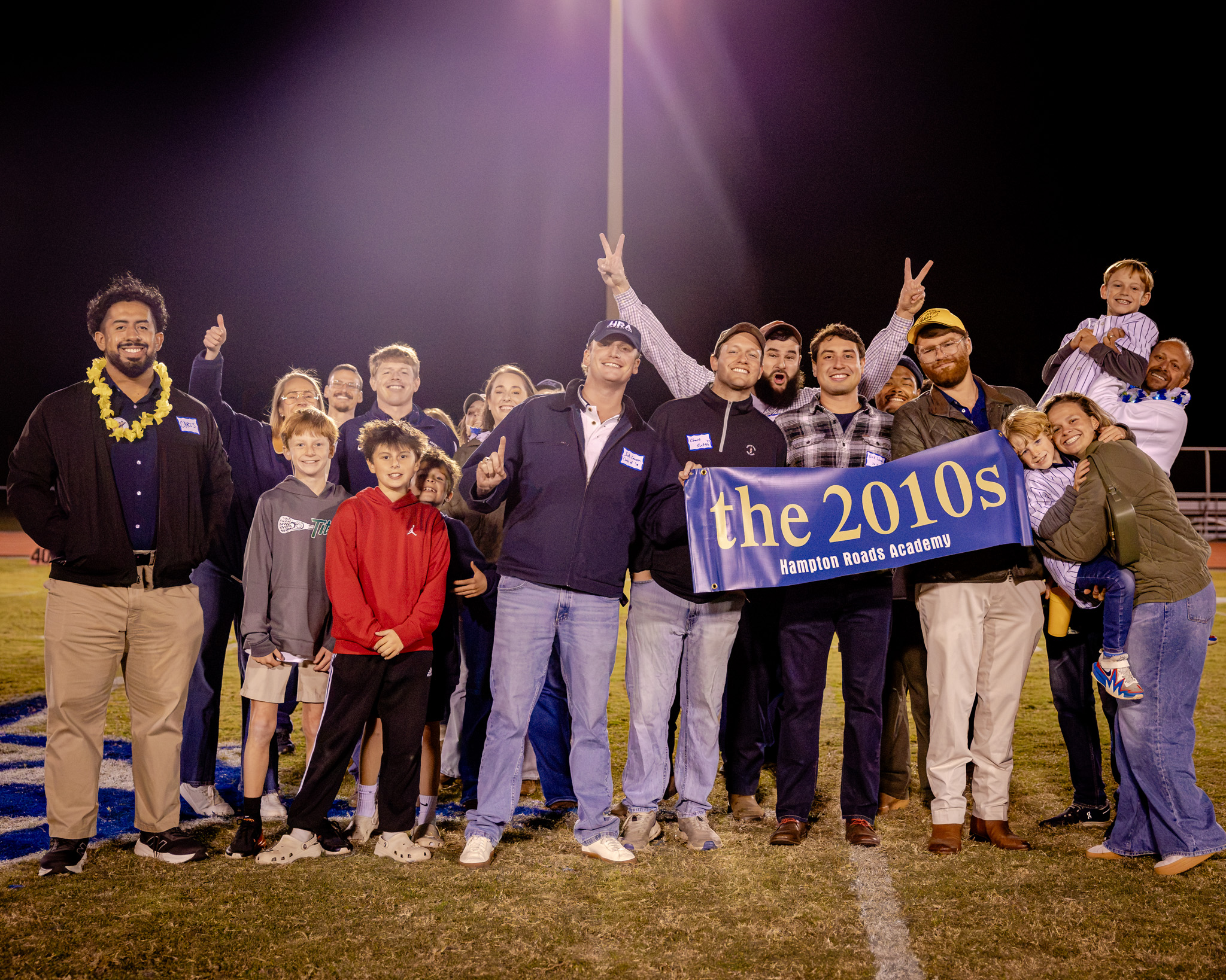 HRA alumni from the 2010s celebrating on the football field at halftime during Homecoming 2026