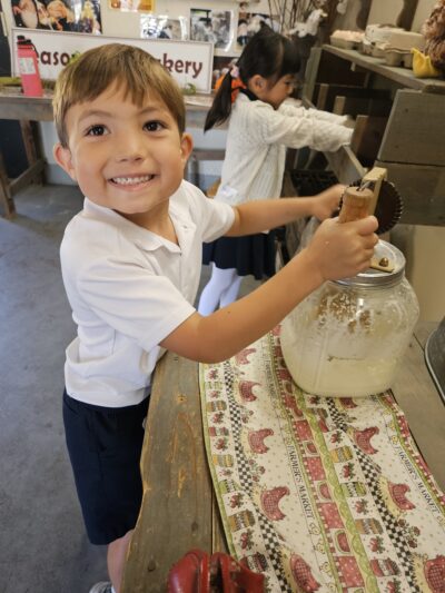 HRA first grader learning to churn butter at the Virginia Beach Farmers Market