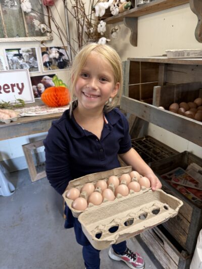 HRA first grader with a carton of eggs at the Virginia Beach Farmers Market