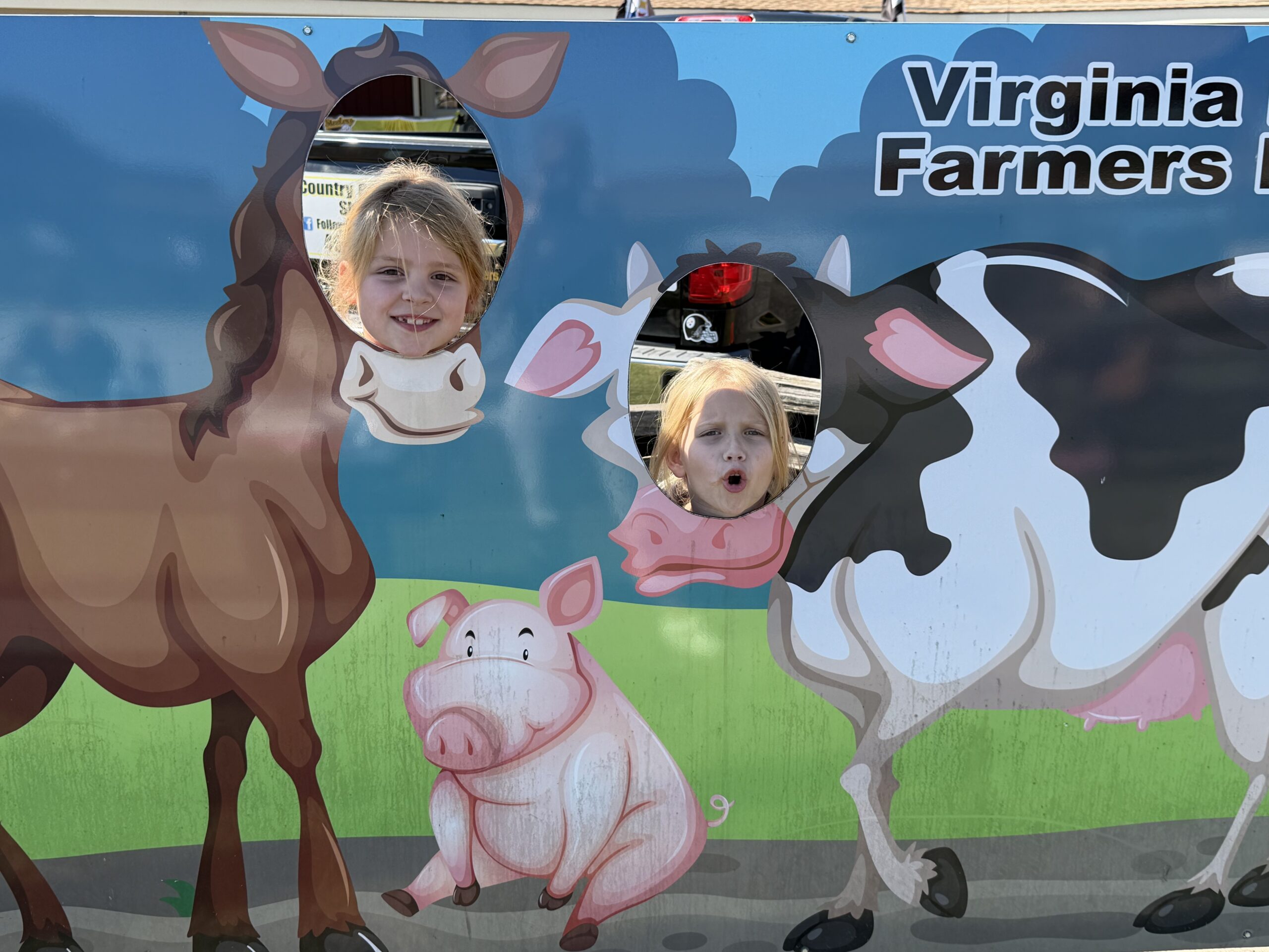 HRA first graders poking their faces through cutouts at the Virginia Beach Farmers Market