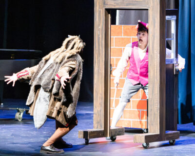 A scared actor opening the door to see the Big Bad Wolf during Virginia Opera's October 2026 production of "The Three Little Pigs" for HRA's Lower School